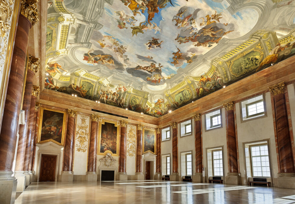 Hercules Hall at Liechtenstein Garden Palace in Vienna Austria. Event space for up to 300 guests seated for gala dinner, with gilded brown marble walls and fresco ceiling